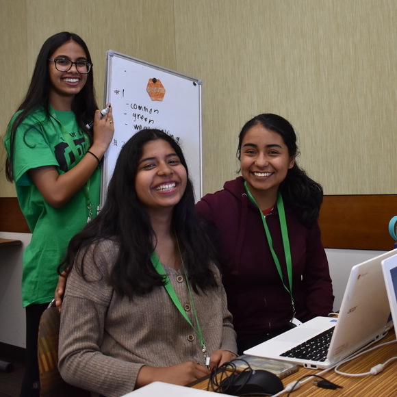 Three teen girls happily learning coding.